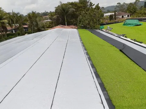 Cubierta larga impermeabilizada con manto aluminio y zona verde, obra de Madepinos