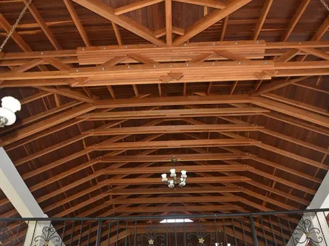 Techo de madera amplio con vigas y lámparas colgantes, obra con materiales Madepinos