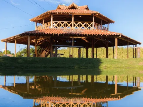 Kiosco de madera con terraza y techo de teja de barro junto a un lago